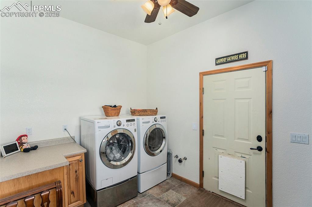 Image 32 of 47: Laundry area with stone finish floors, washing machine and dryer, and a cei