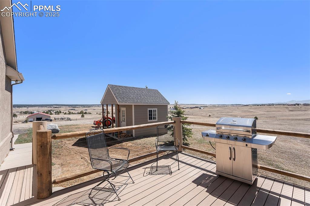 Image 35 of 47: Wooden deck featuring area for grilling, an outdoor structure, and a view o