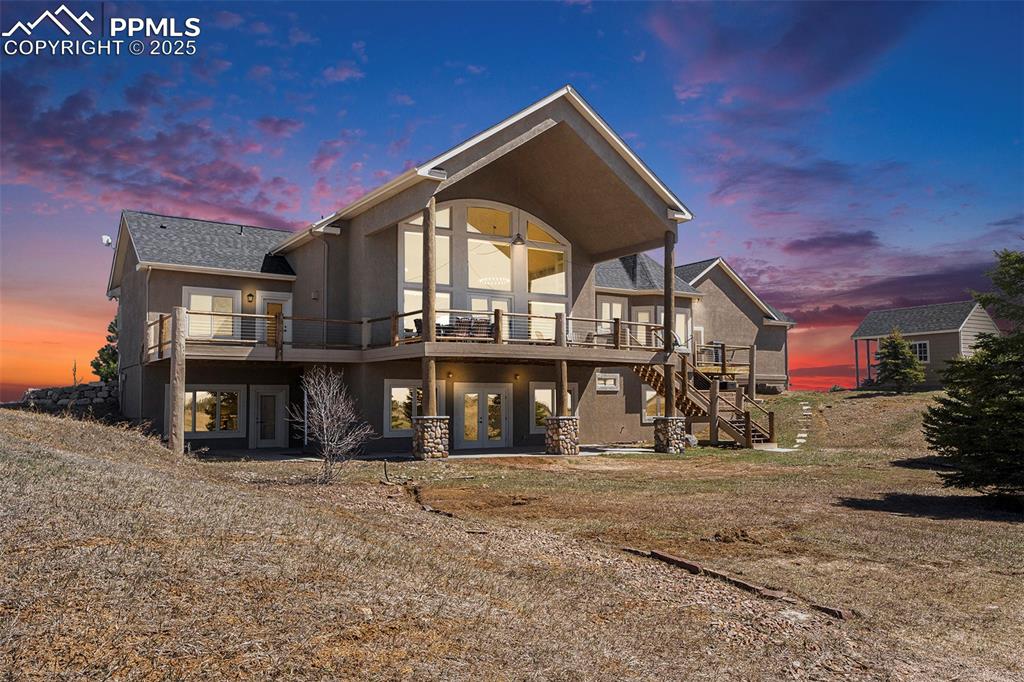 Image 4 of 47: Back of property at dusk featuring a patio, stucco siding, stairway, and a