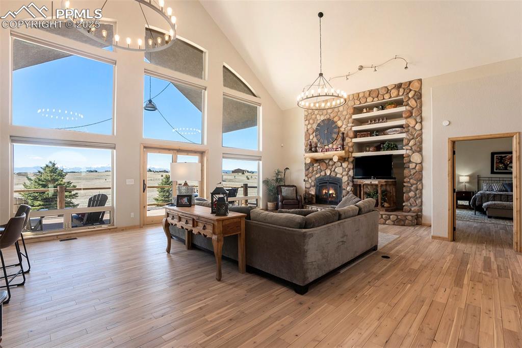 Image 6 of 47: Living area featuring a chandelier, high vaulted ceiling, light wood-style