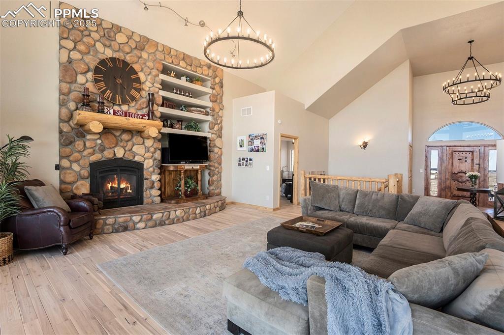 Image 8 of 47: Living room with a chandelier, high vaulted ceiling, wood finished floors,
