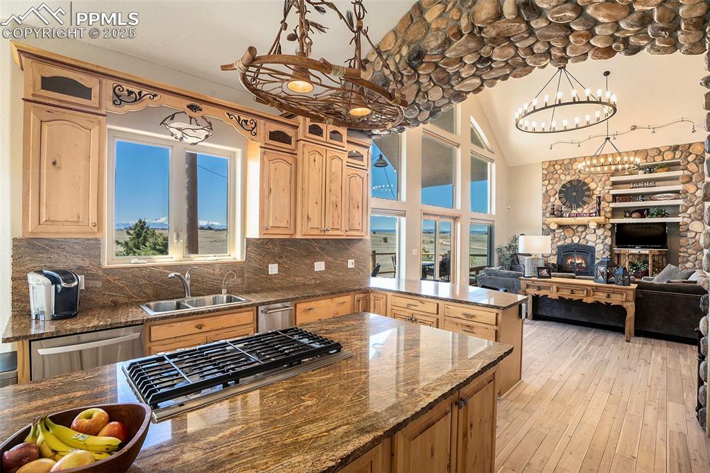 Image 9 of 47: Kitchen with dark stone counters, a stone fireplace, tasteful backsplash, o
