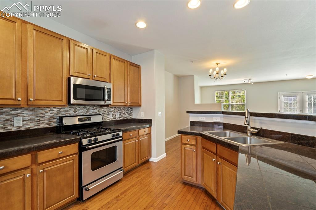 Image 11 of 48: Kitchen with stainless steel appliances, light wood-style floors, decorativ