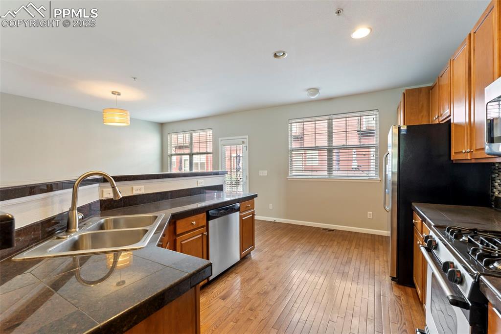 Image 15 of 48: Kitchen featuring brown cabinetry, light wood-type flooring, appliances wit