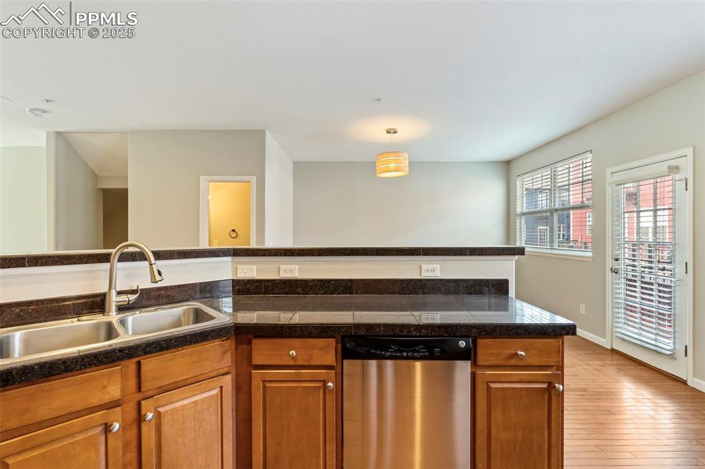 Image 16 of 48: Kitchen featuring tile counters, dishwasher, brown cabinetry, and hardwood