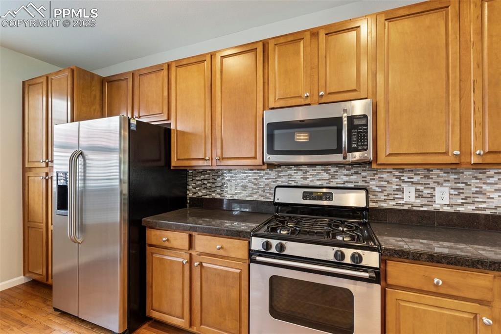 Image 18 of 48: Kitchen with appliances with stainless steel finishes, light wood-style flo
