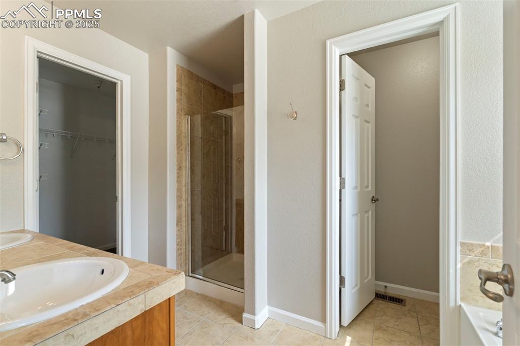 Image 26 of 48: Bathroom with a stall shower, tile patterned flooring, a spacious closet, d