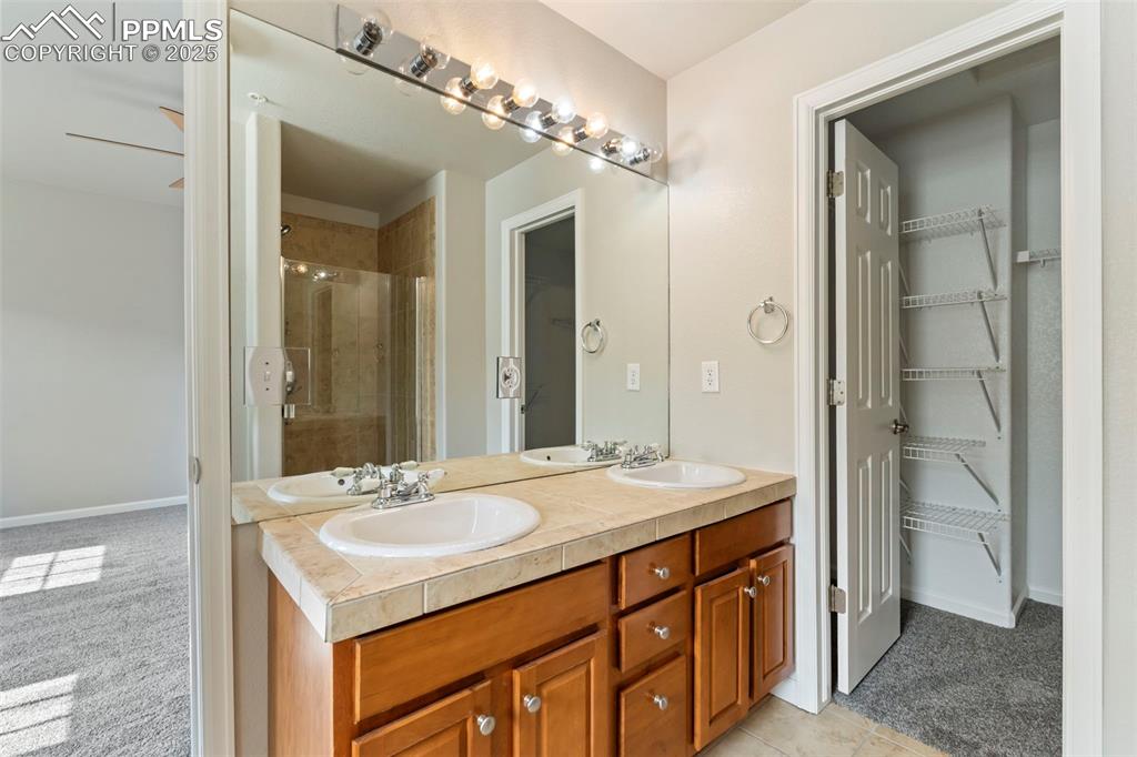 Image 27 of 48: Full bathroom with double vanity, a shower stall, and a walk in closet