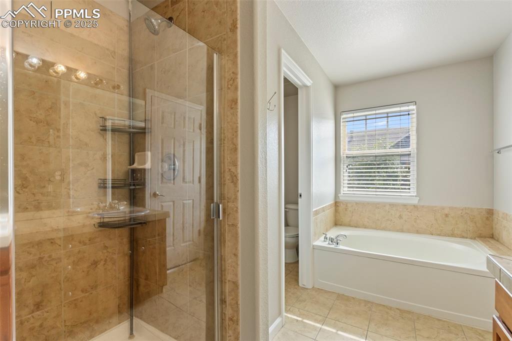 Image 29 of 48: Full bathroom with tile patterned floors, a stall shower, and a garden tub