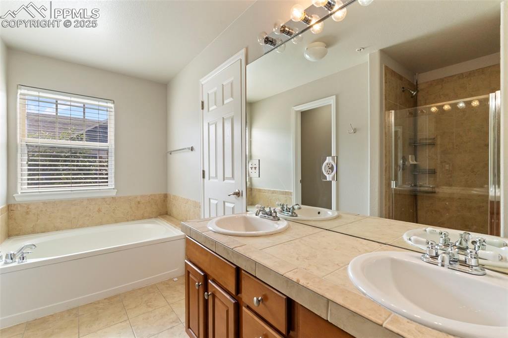 Image 30 of 48: Full bathroom with double vanity, a bath, tile patterned flooring, and a st