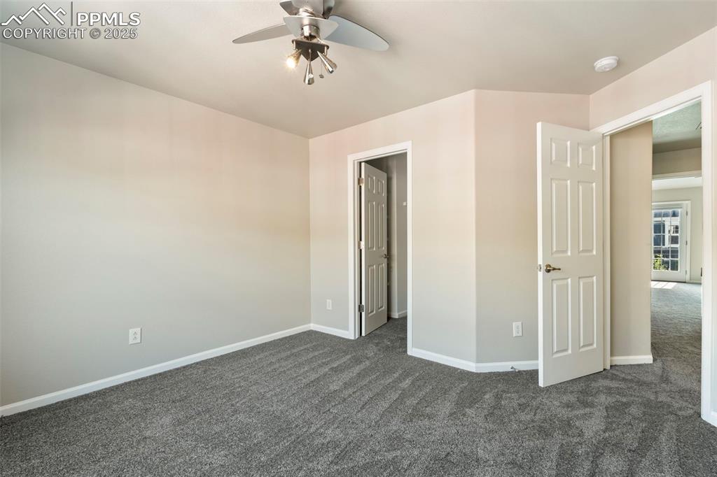 Image 36 of 48: Unfurnished bedroom featuring dark colored carpet and a ceiling fan