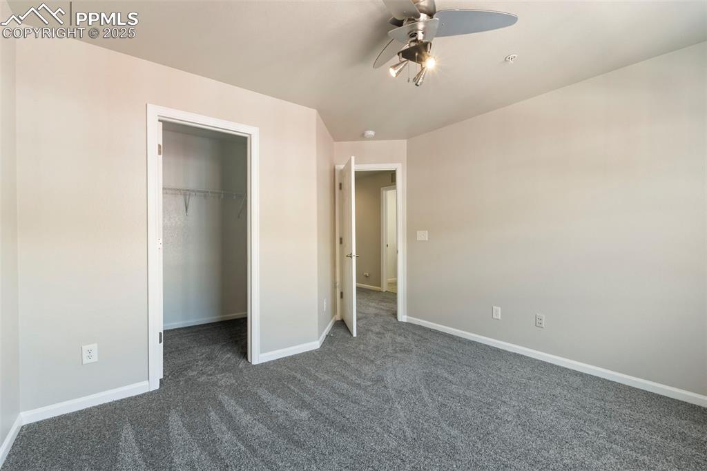 Image 37 of 48: Unfurnished bedroom featuring dark colored carpet, a walk in closet, and a