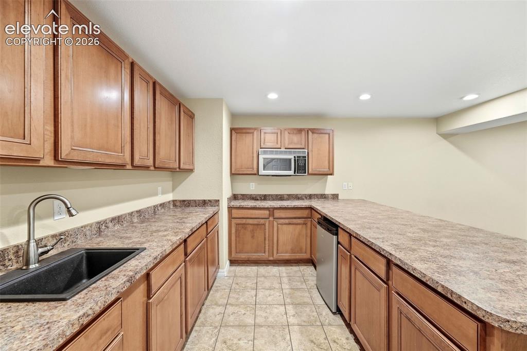 Image 32 of 47: Kitchenette Features Sink and Stainless Steel Microwave/Dishwasher