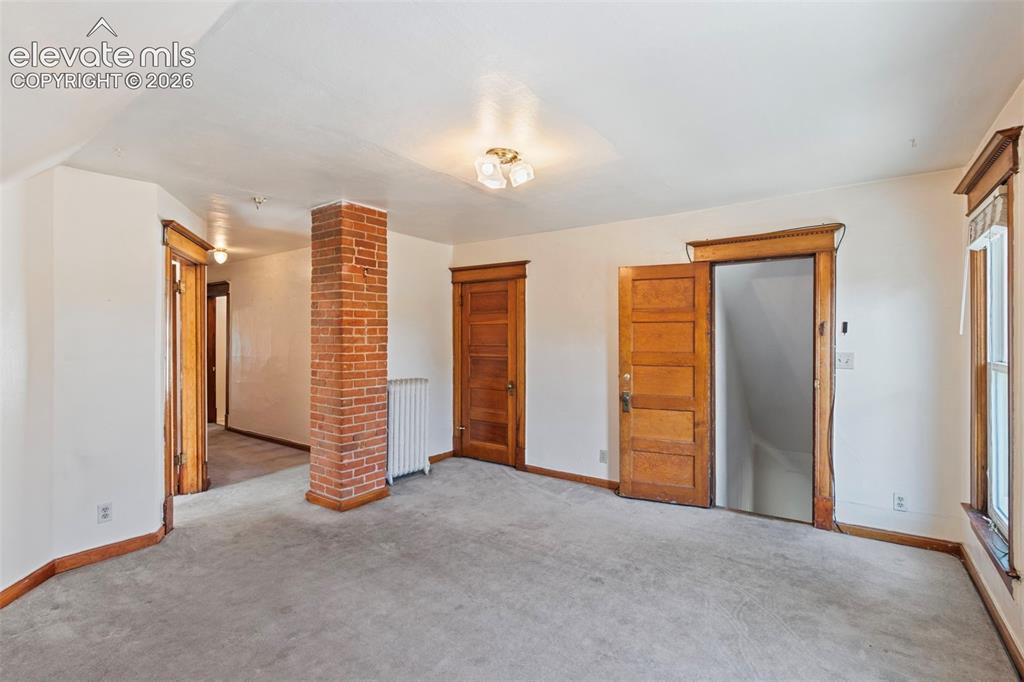 Image 18 of 31: Upper level living area featuring exposed brick and storage closet.