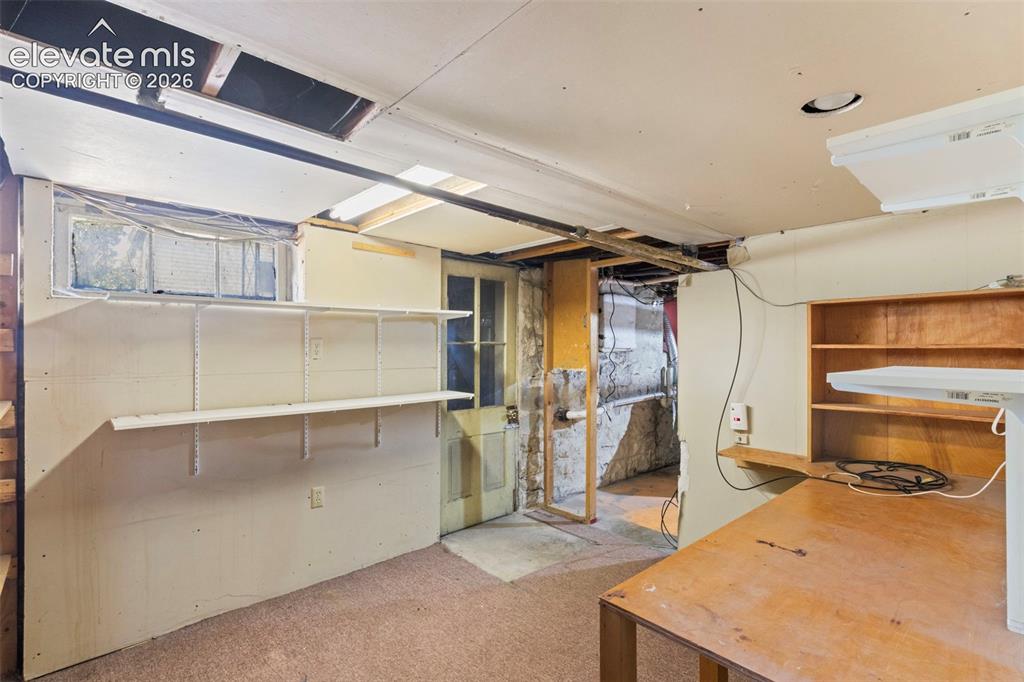 Image 26 of 31: Basement with desk, storage shelves and walk out.
