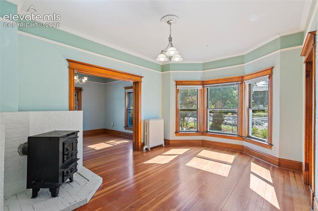 Image 9 of 31: Dining room with wood burning stove, bay windows, pocket doors and beautifu