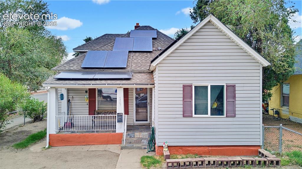 Caption: Exterior featuring light-colored siding, a covered porch with white railing, a gabled roof, and sola