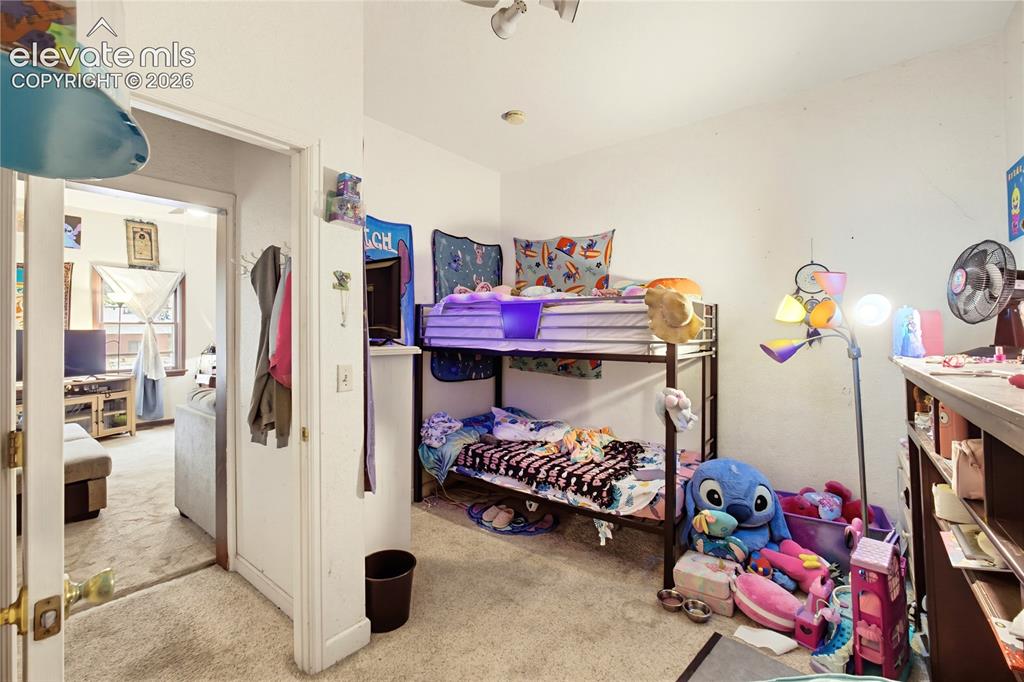 Image 10 of 26: Carpeted flooring, vaulted ceiling, and built-in shelving