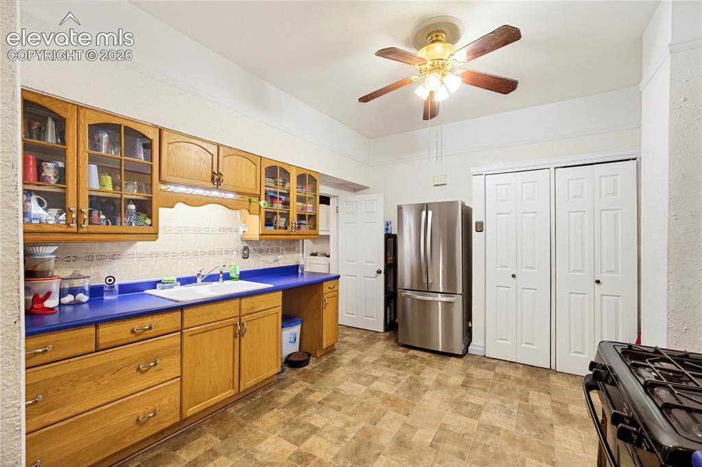 Image 17 of 26: Full kitchen featuring wood-finish cabinetry with glass panel accents, a st
