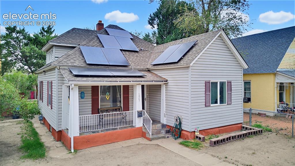 Image 2 of 26: Gabled roofline with solar panels, vinyl siding, covered front porch, and f