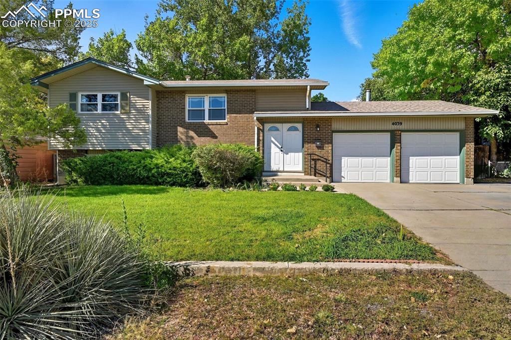 Caption: Tri-level home featuring a garage, brick siding, concrete driveway, and a front lawn