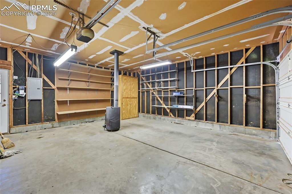 Image 19 of 29: Garage with heat source and built in shelving and a workspace out of view