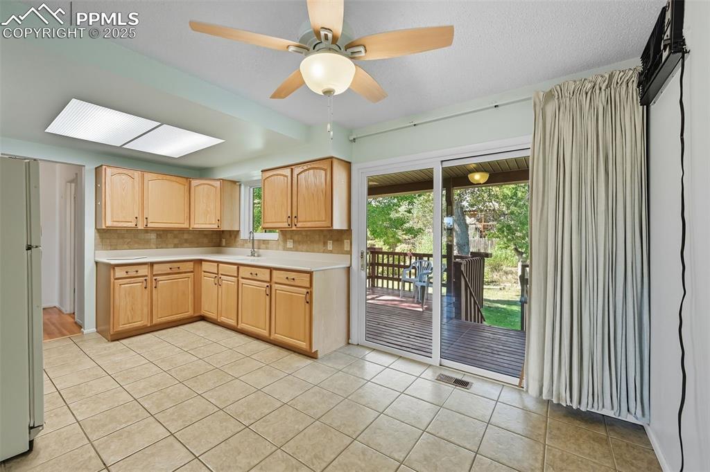 Image 4 of 29: Kitchen with light brown cabinets, freestanding refrigerator, light tile pa