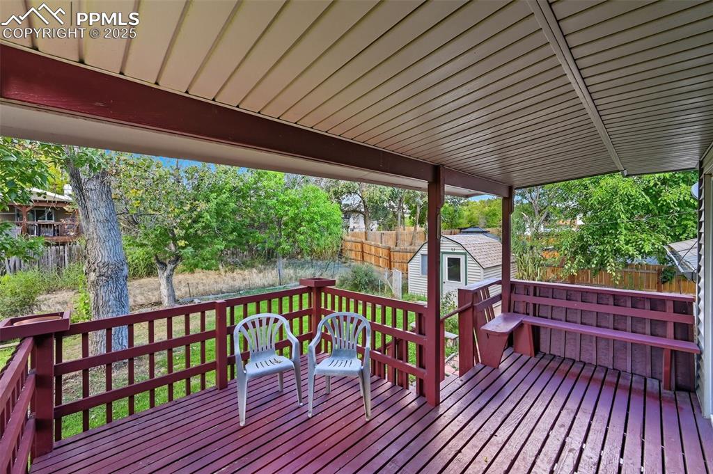 Image 8 of 29: Wooden terrace with built in seating and a fenced backyard