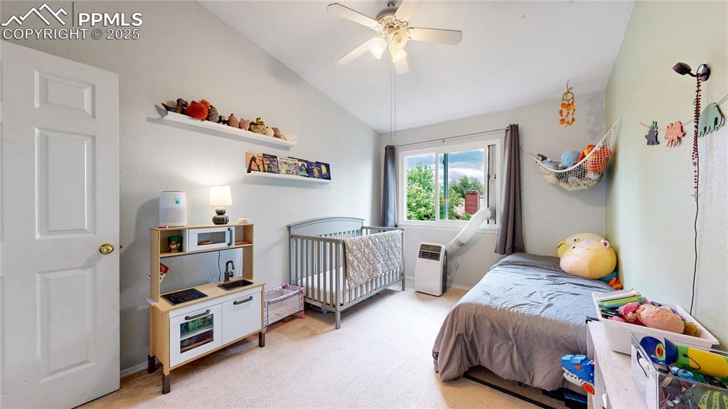 Image 20 of 37: Bedroom with light carpet, vaulted ceiling, radiator heating unit, and a ce