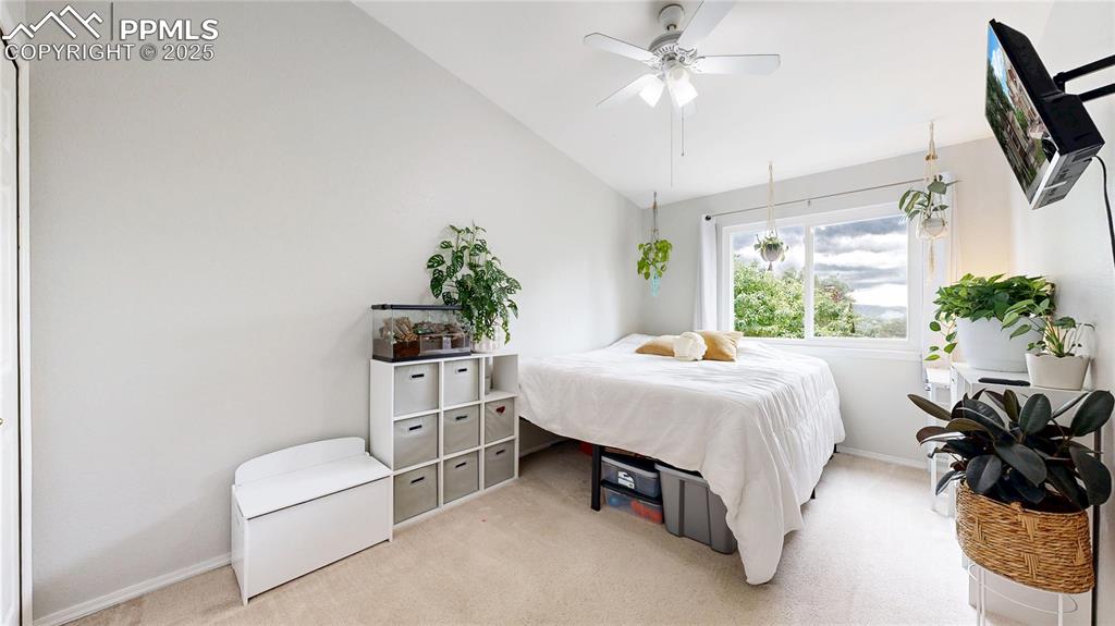 Image 22 of 37: Bedroom with vaulted ceiling, light carpet, and a ceiling fan