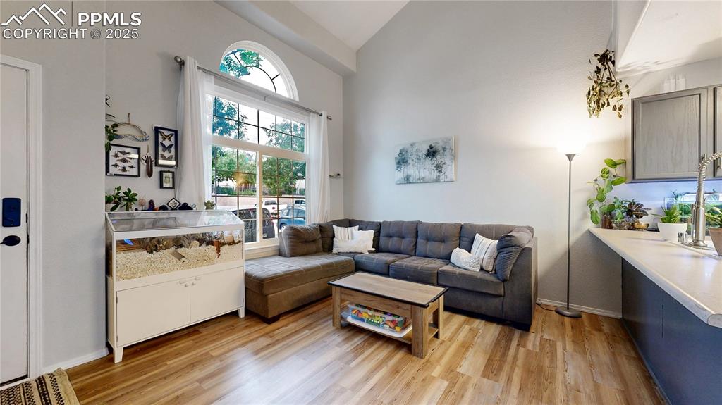 Image 5 of 37: Living area featuring light wood finished floors and high vaulted ceiling