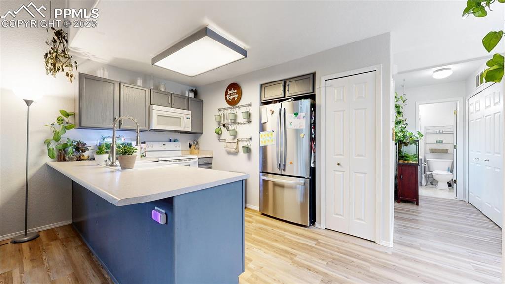 Image 7 of 37: Kitchen featuring white appliances, a peninsula, light wood-type flooring,