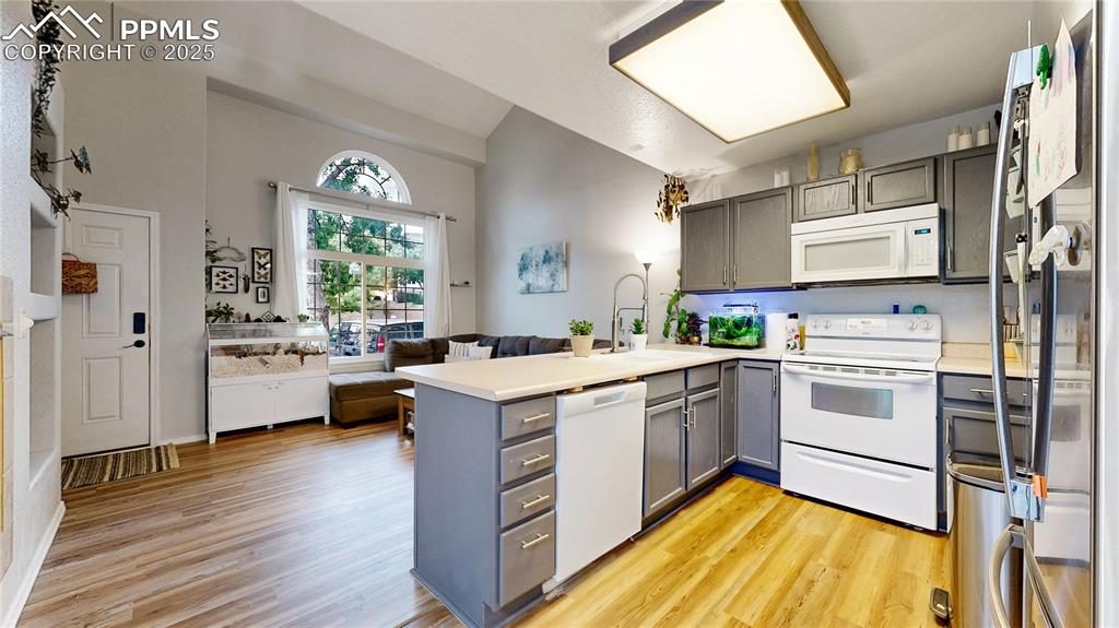 Image 8 of 37: Kitchen featuring white appliances, gray cabinets, a peninsula, open floor