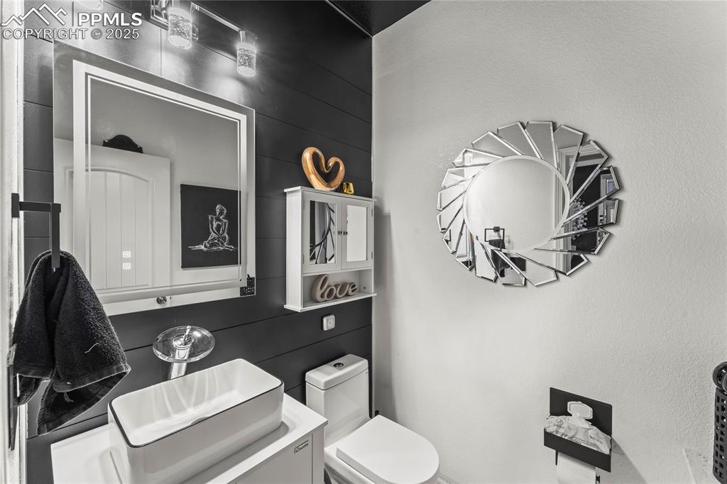 Image 14 of 39: Half bathroom featuring vanity and wood walls