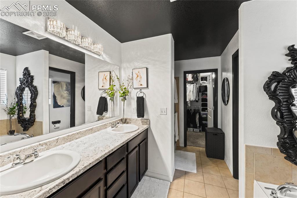 Image 25 of 39: Bathroom with a garden tub, double vanity, a spacious closet, light tile pa
