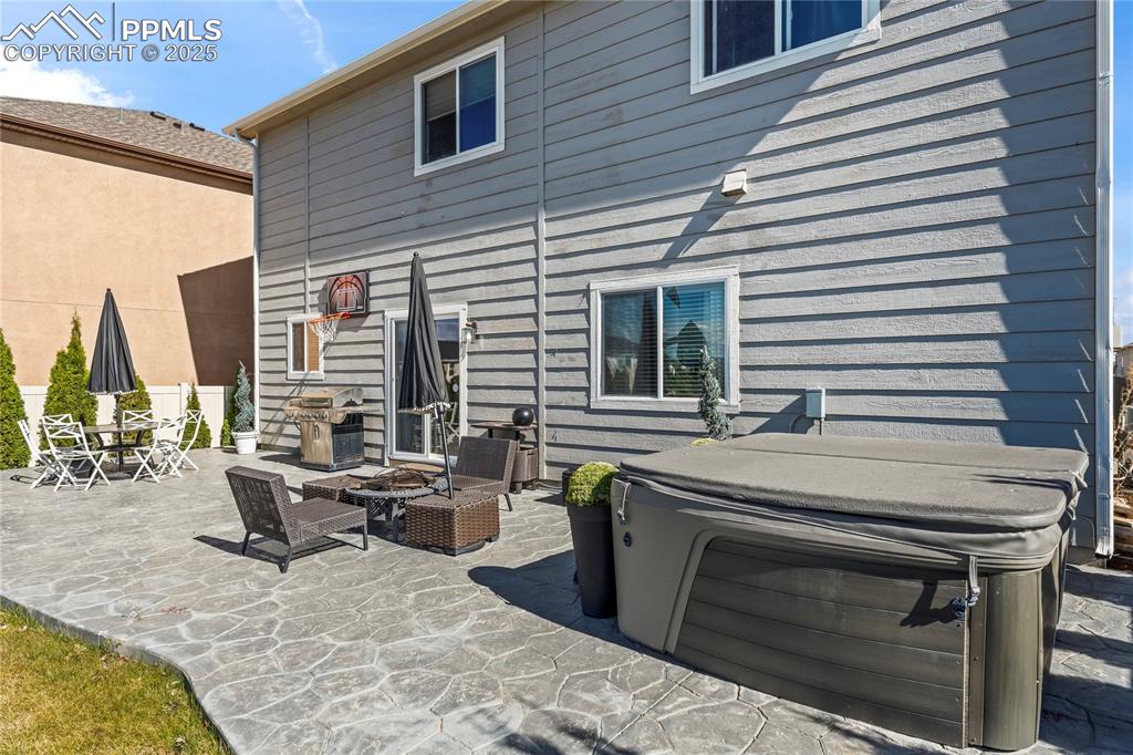 Image 34 of 39: Back of property featuring a hot tub, a patio, and a fire pit