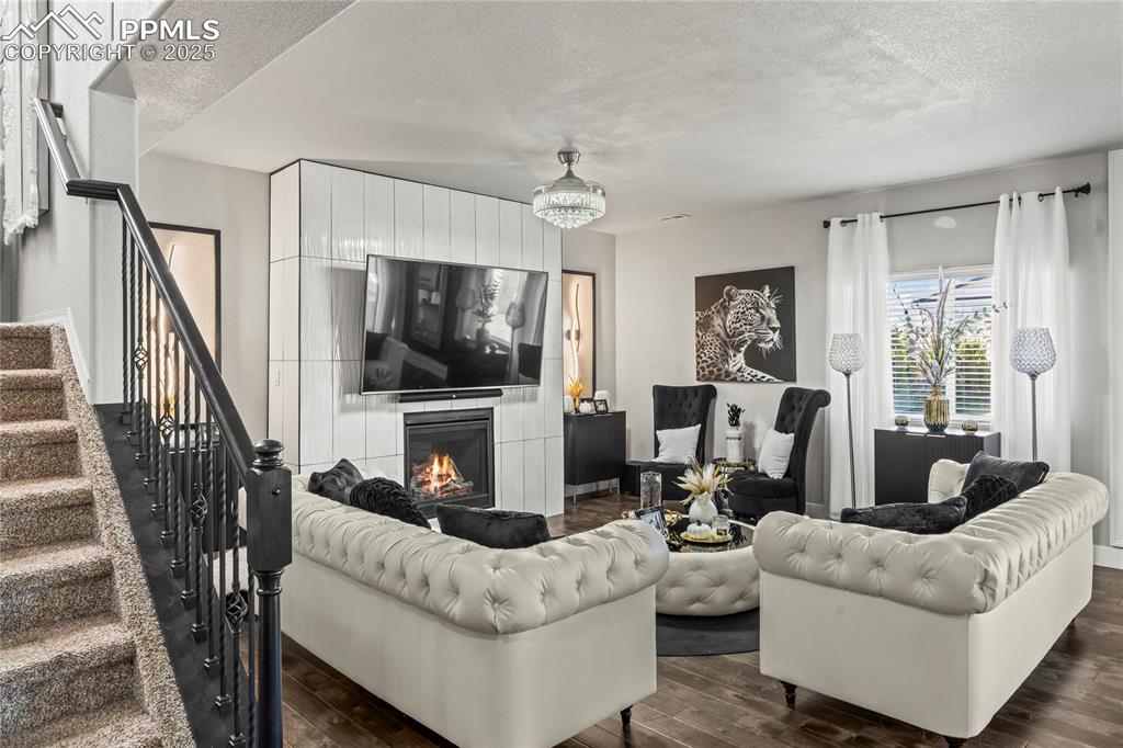 Image 6 of 39: Living area featuring a textured ceiling, dark wood-style floors, stairs, a