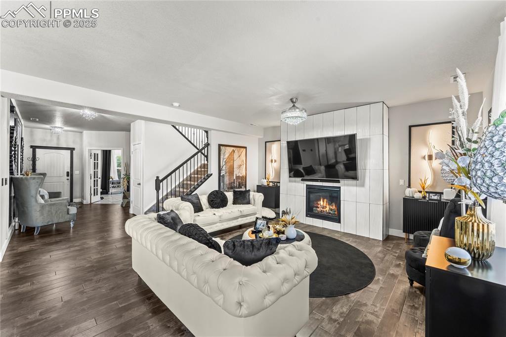 Image 7 of 39: Living area featuring a fireplace, dark wood-style floors, stairway, and a 