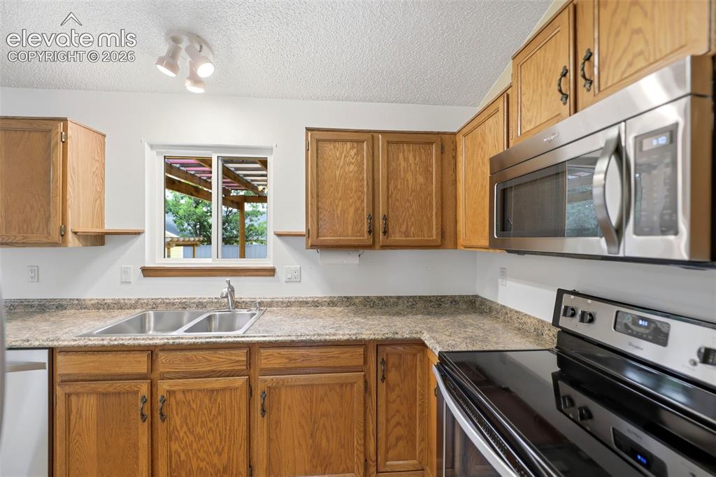 Image 13 of 50: Kitchen featuring wood cabinetry, stainless steel appliances, a double basi