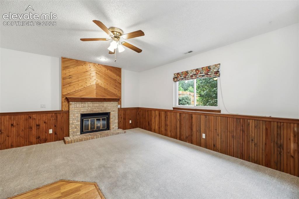 Image 17 of 50: Spacious room featuring a brick fireplace with a wood-finish accent wall, w