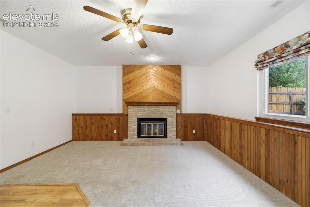 Image 18 of 50: Carpeted room featuring a brick fireplace with a wood-finish mantel and a d