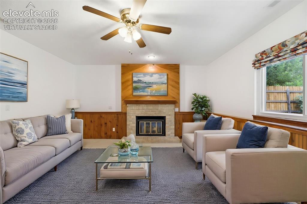 Image 19 of 50: Virtually Staged - Living area featuring a brick fireplace with wood paneli
