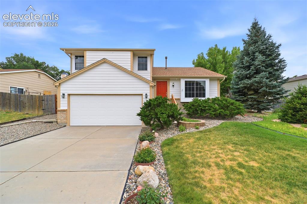 Image 2 of 50: Two-story residence featuring white siding, an attached garage, a concrete