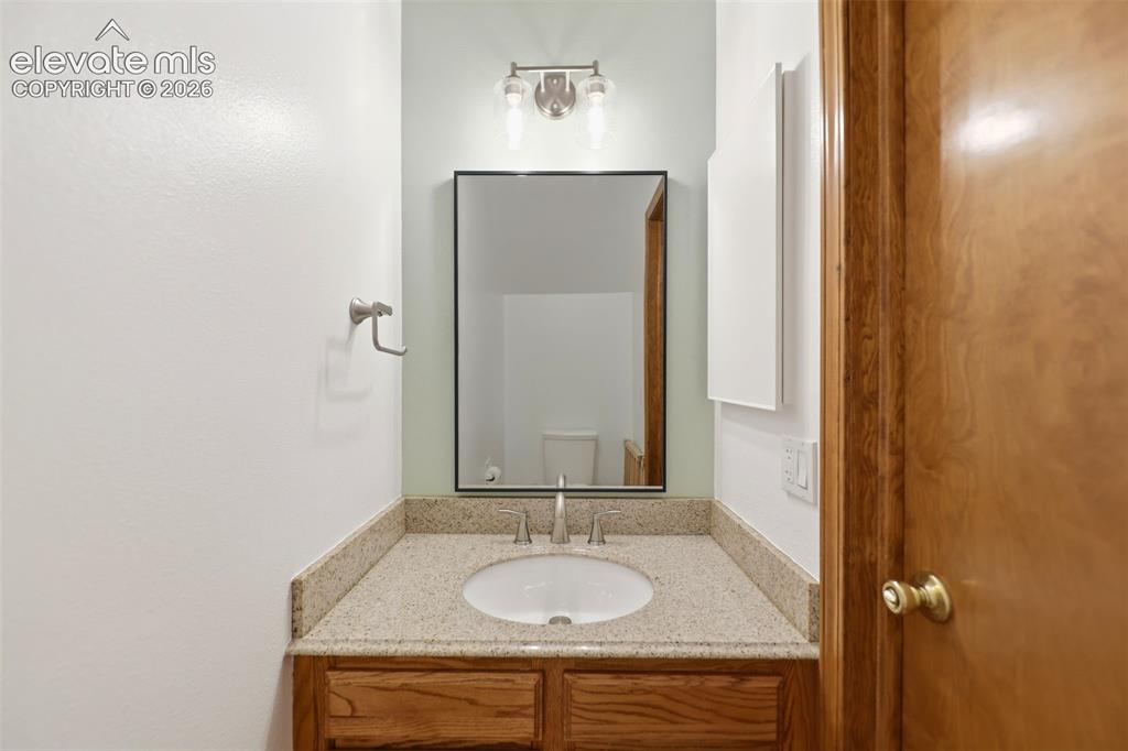 Image 22 of 50: Bathroom vanity featuring a granite-finish countertop with an undermount si