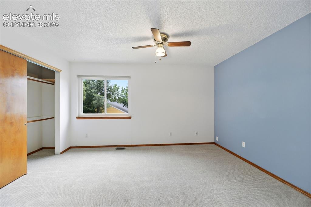 Image 23 of 50: Carpeted room featuring a single window, a ceiling fan, a painted accent wa