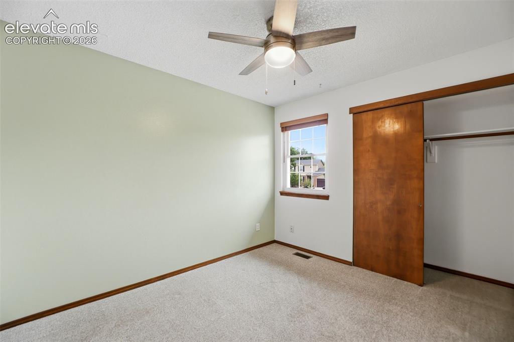 Image 28 of 50: Carpeted room featuring a ceiling fan with integrated lighting, a window wi