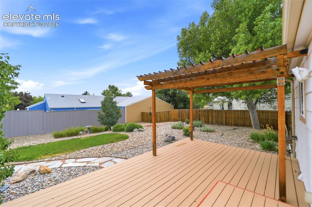 Image 35 of 50: Expansive outdoor living area featuring a spacious deck with a wood pergola