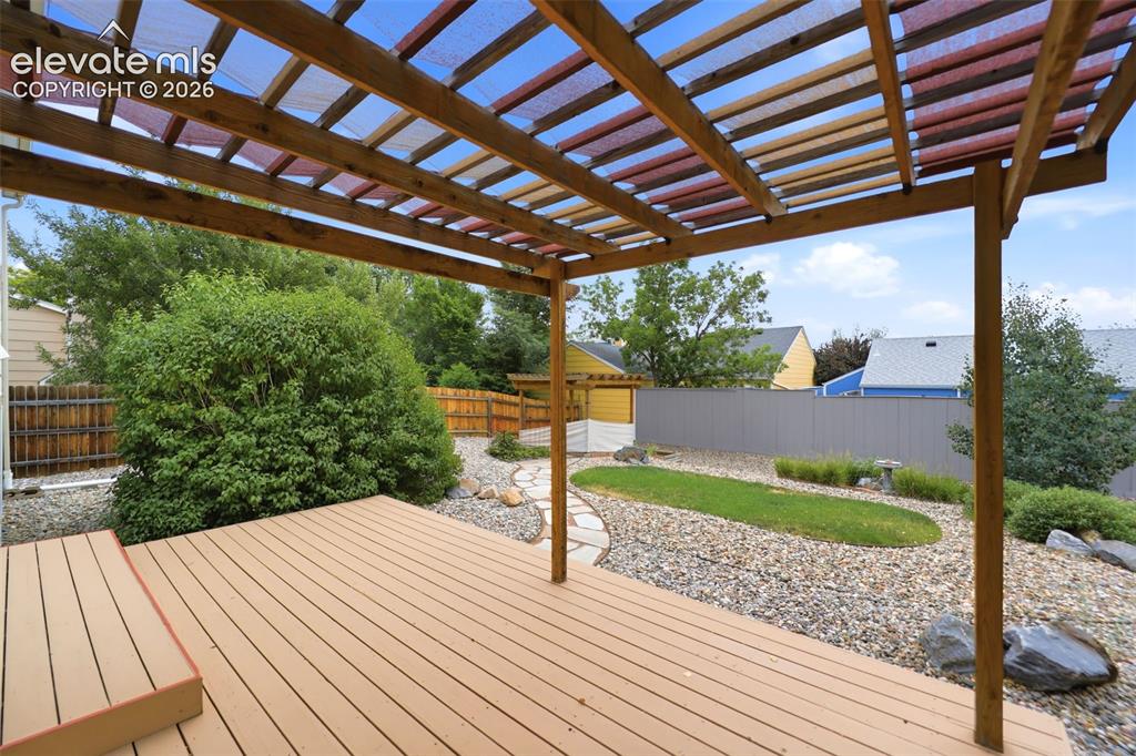 Image 36 of 50: Expansive outdoor deck with a slatted wood pergola, a stone pathway, and a