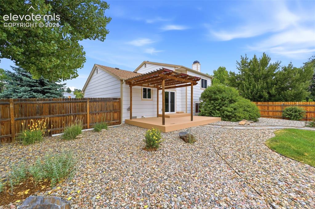 Image 38 of 50: Rear exterior featuring a spacious deck with an overhead pergola, white sid