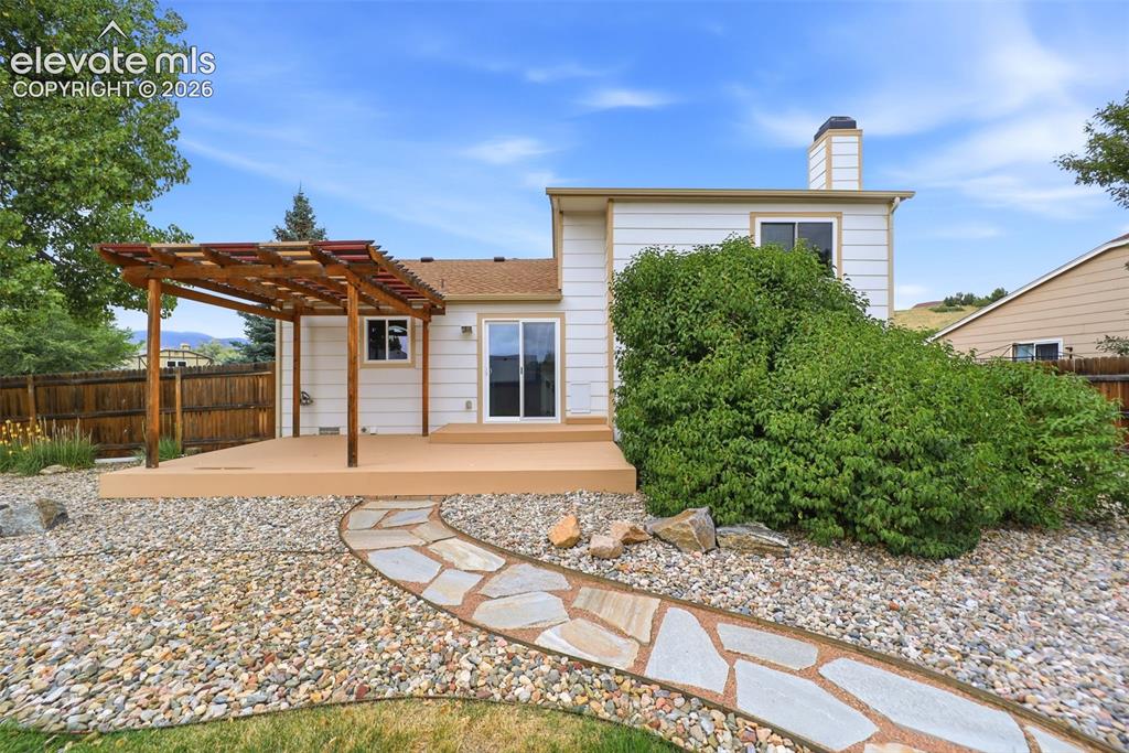 Image 40 of 50: Rear exterior featuring a deck with an attached pergola, sliding glass door